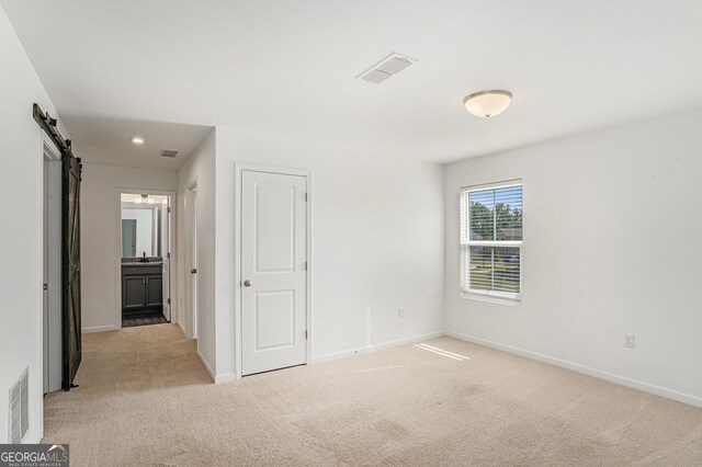 carpeted empty room with a barn door