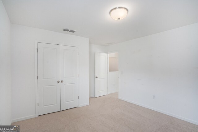 unfurnished bedroom featuring light carpet and a closet