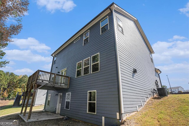 rear view of house featuring a yard, a patio area, a wooden deck, and central AC unit