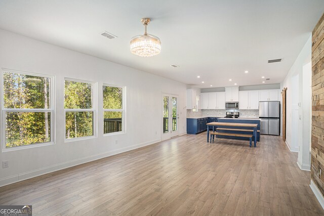 kitchen with white cabinetry, appliances with stainless steel finishes, light wood-type flooring, and decorative backsplash