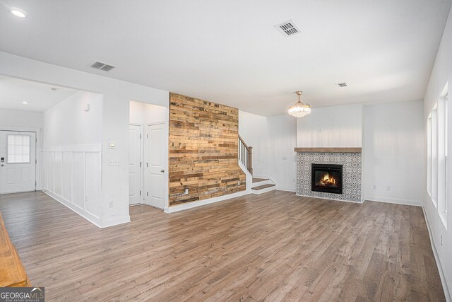 unfurnished living room with a tiled fireplace, hardwood / wood-style flooring, and plenty of natural light