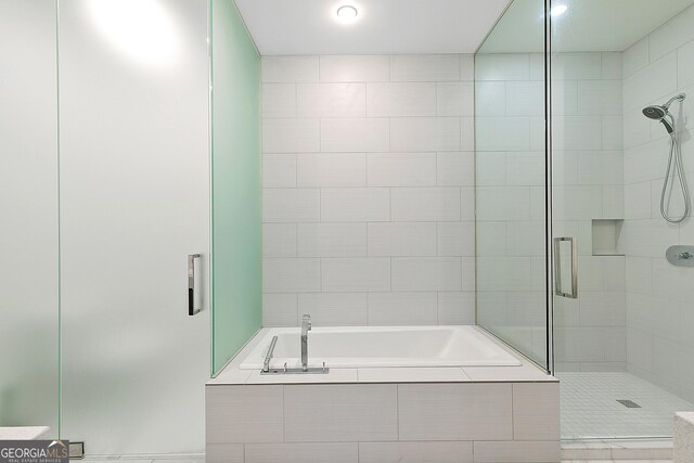 bathroom featuring a garden tub and a shower stall