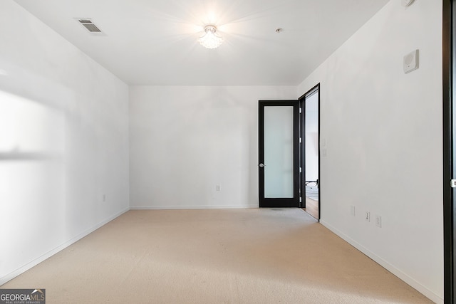 empty room featuring baseboards, visible vents, and light colored carpet