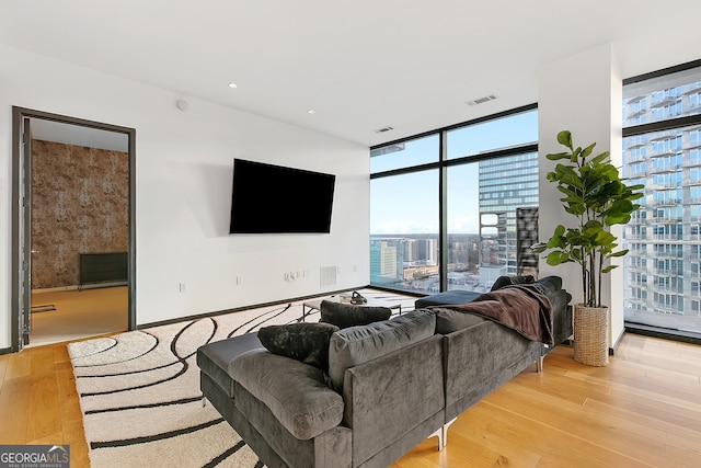 living room with visible vents, light wood-type flooring, a healthy amount of sunlight, and floor to ceiling windows