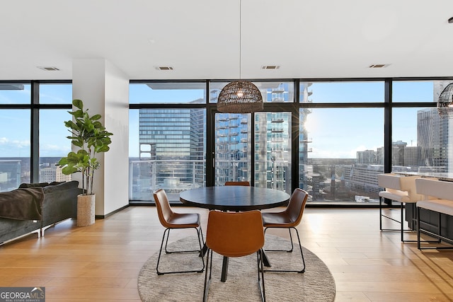 dining space featuring a wall of windows, visible vents, a view of city, and hardwood / wood-style flooring