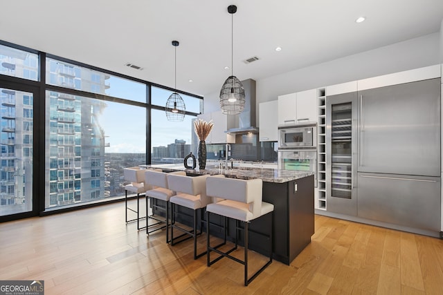 kitchen with built in appliances, visible vents, light wood finished floors, and expansive windows