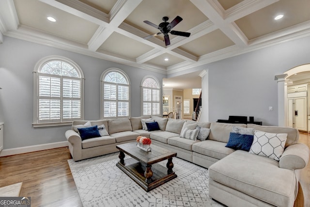 living room with ceiling fan, ornamental molding, light hardwood / wood-style flooring, and beamed ceiling