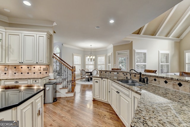 kitchen featuring sink, light stone countertops, hanging light fixtures, and light hardwood / wood-style floors