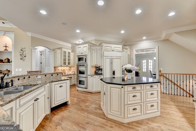 kitchen with light hardwood / wood-style flooring, sink, built in appliances, crown molding, and a center island