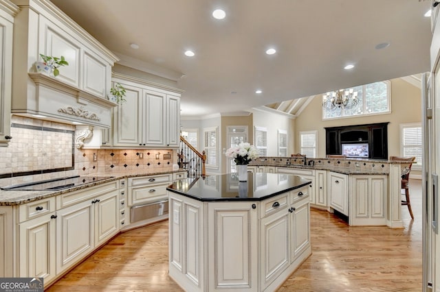 kitchen featuring black electric cooktop, light wood-type flooring, kitchen peninsula, and a kitchen island