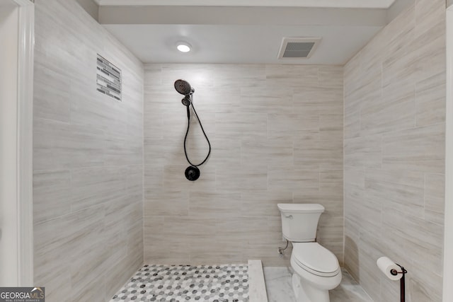 bathroom with a tile shower and toilet