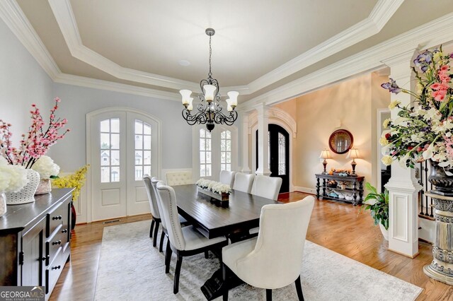 entryway featuring hardwood / wood-style flooring, a chandelier, a towering ceiling, crown molding, and french doors