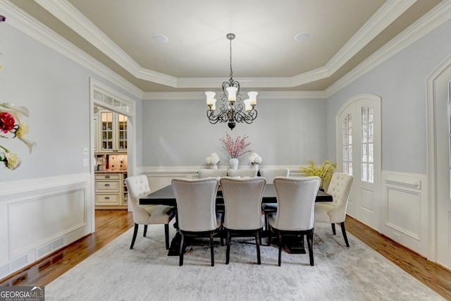 dining space featuring an inviting chandelier, crown molding, hardwood / wood-style floors, and a tray ceiling