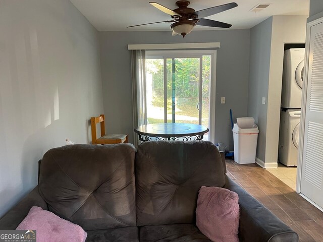 living room featuring ceiling fan, light hardwood / wood-style floors, and stacked washing maching and dryer