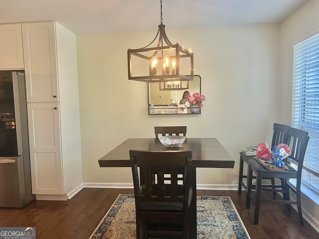 dining area featuring dark wood-type flooring, a textured ceiling, and an inviting chandelier