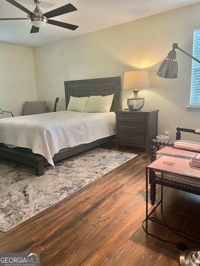 bedroom with a textured ceiling, hardwood / wood-style flooring, and ceiling fan