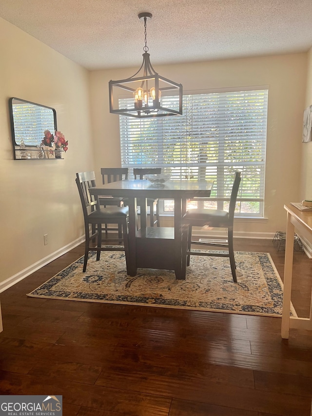 dining area featuring a textured ceiling, wood-type flooring, and an inviting chandelier