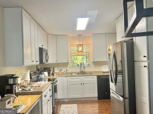 kitchen featuring hardwood / wood-style floors, white cabinetry, black appliances, sink, and butcher block countertops