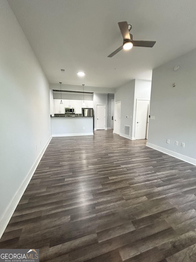 unfurnished living room featuring ceiling fan and dark wood-type flooring