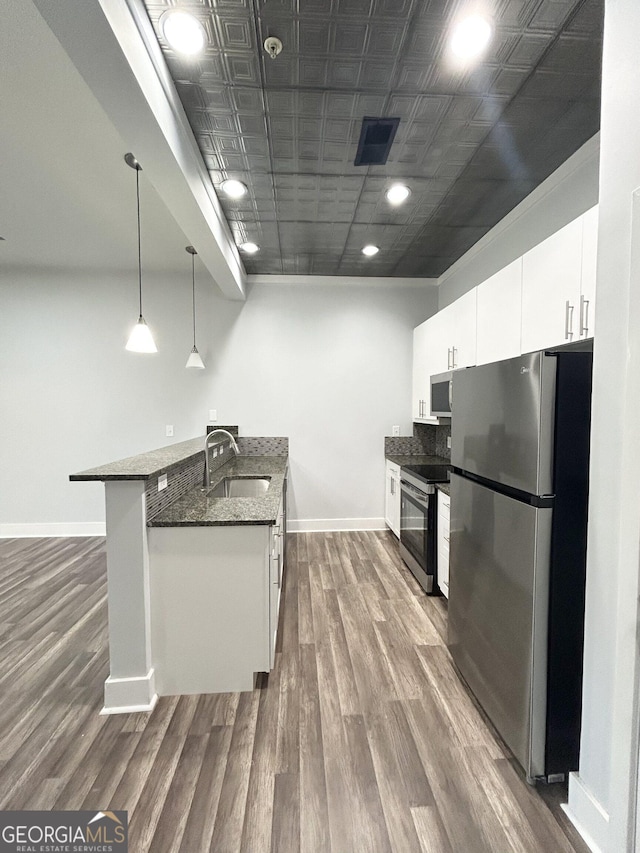 kitchen featuring dark stone countertops, pendant lighting, white cabinets, and stainless steel appliances