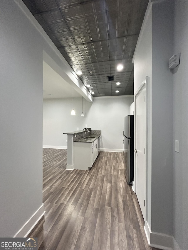 kitchen with white cabinetry, sink, dark wood-type flooring, stainless steel fridge, and decorative light fixtures