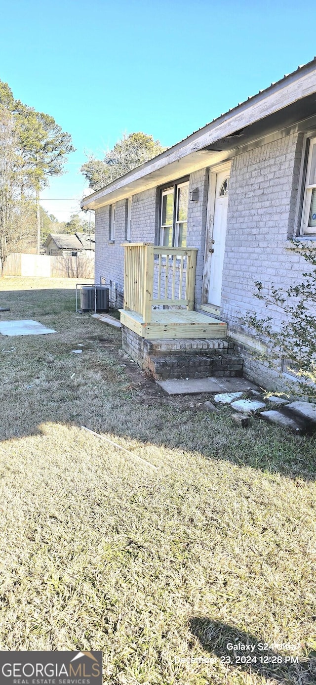 view of front of home with central AC unit and a front lawn