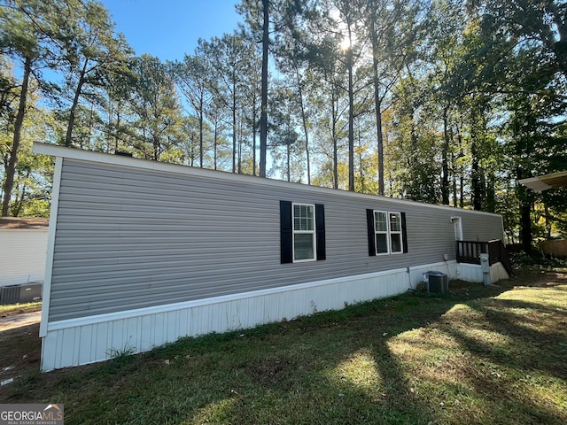 view of side of home with central air condition unit and a lawn