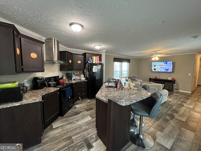 kitchen featuring black appliances, a kitchen bar, a textured ceiling, wall chimney exhaust hood, and a kitchen island with sink