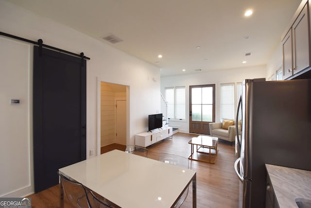 kitchen featuring a barn door, hardwood / wood-style flooring, and stainless steel refrigerator