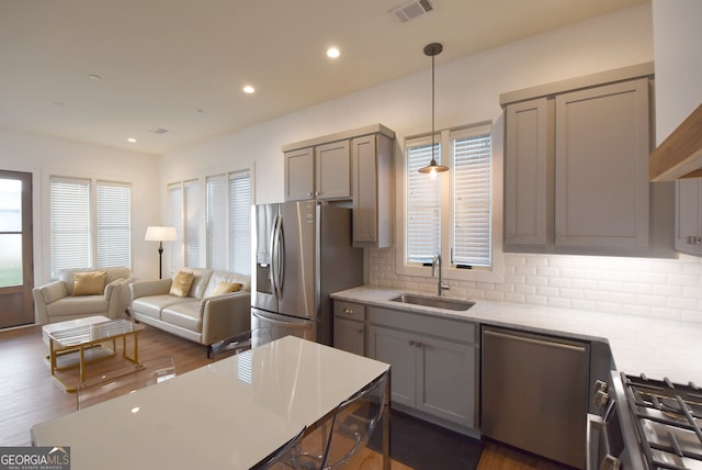 kitchen featuring sink, appliances with stainless steel finishes, dark wood-type flooring, and decorative light fixtures