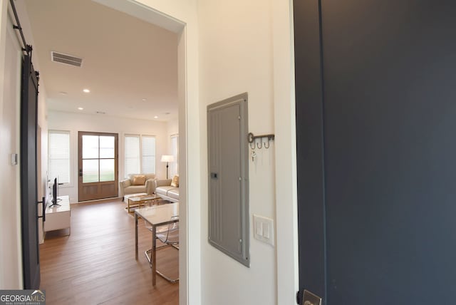 hall featuring hardwood / wood-style flooring, electric panel, and a barn door