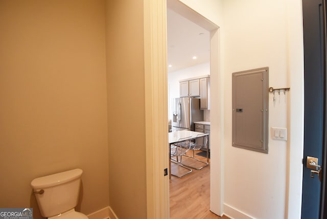 bathroom featuring toilet, hardwood / wood-style flooring, and electric panel