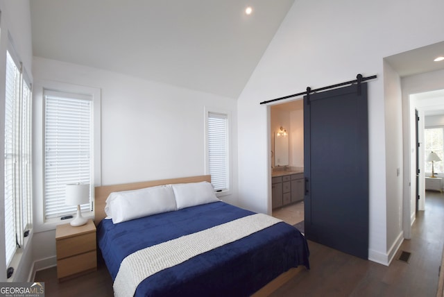 bedroom featuring dark hardwood / wood-style floors, ensuite bathroom, high vaulted ceiling, and a barn door