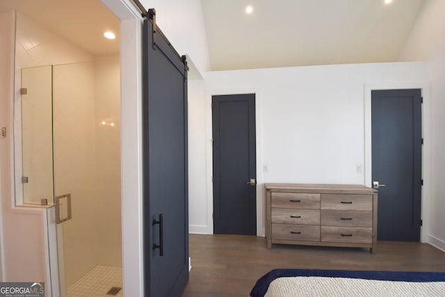 unfurnished bedroom with dark hardwood / wood-style floors, a barn door, and vaulted ceiling