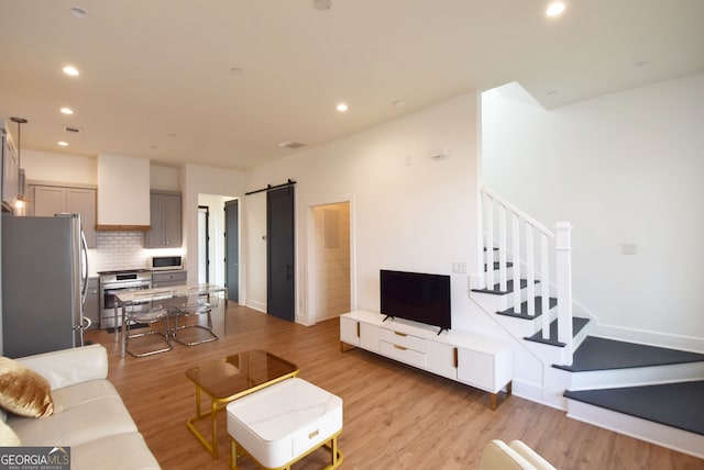 living room with a barn door and light hardwood / wood-style flooring