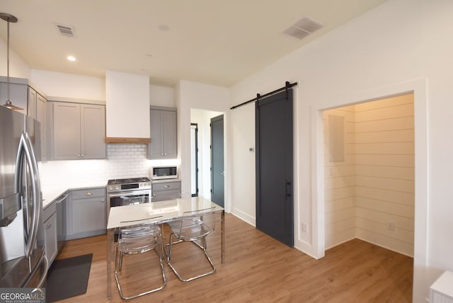 kitchen featuring appliances with stainless steel finishes, light wood-type flooring, and gray cabinets