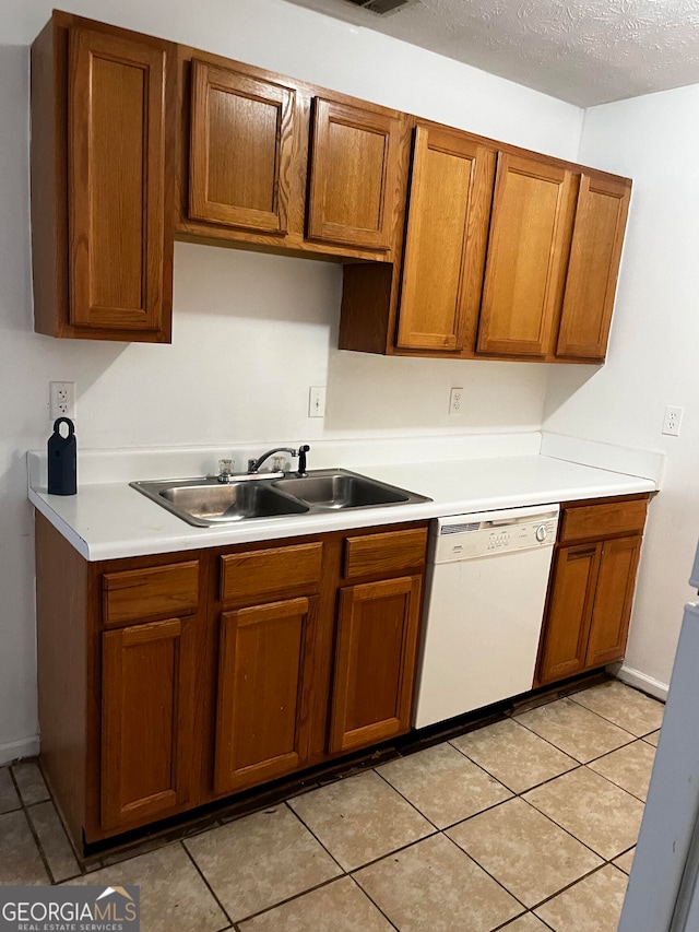 kitchen featuring white dishwasher, sink, a textured ceiling, and light tile patterned floors