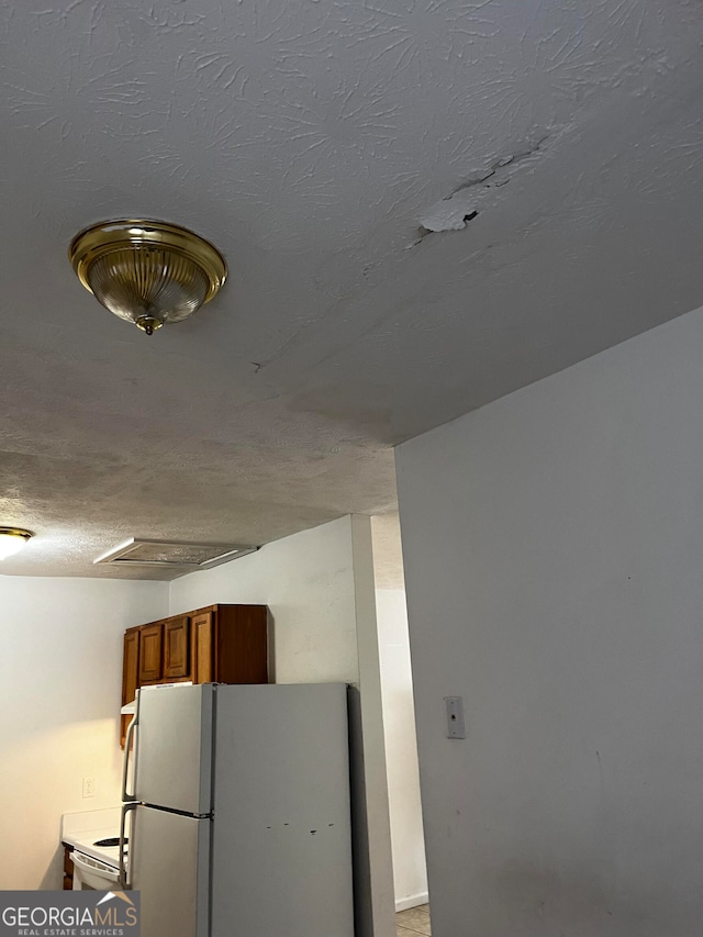 interior space with a textured ceiling and white refrigerator