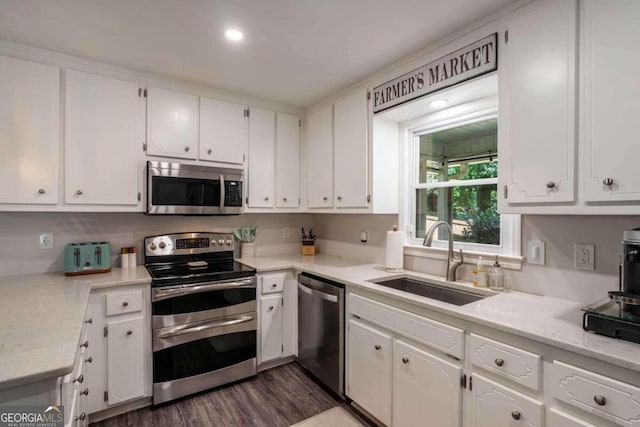 kitchen with white cabinetry, light stone countertops, dark wood-type flooring, sink, and stainless steel appliances