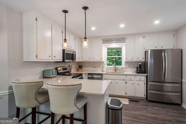 kitchen featuring hanging light fixtures, kitchen peninsula, sink, white cabinetry, and appliances with stainless steel finishes