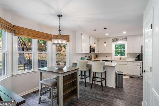 kitchen featuring a center island, white cabinetry, hanging light fixtures, and dark hardwood / wood-style floors