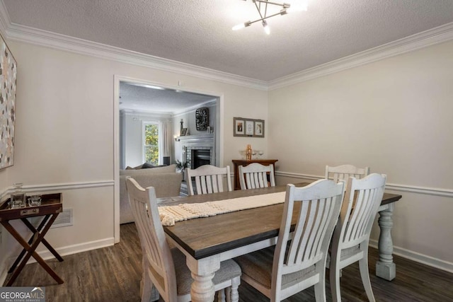 dining space featuring a textured ceiling, dark hardwood / wood-style flooring, a chandelier, and ornamental molding