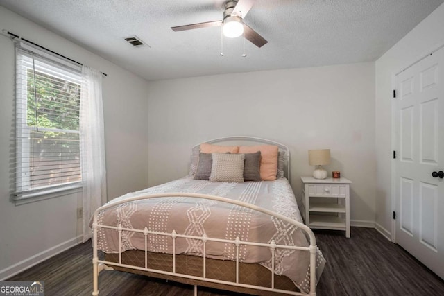 bedroom with ceiling fan, a textured ceiling, and dark hardwood / wood-style floors