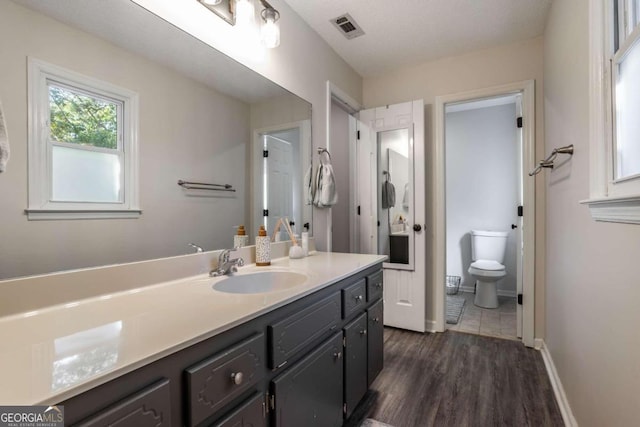 bathroom featuring vanity, hardwood / wood-style floors, a textured ceiling, and toilet