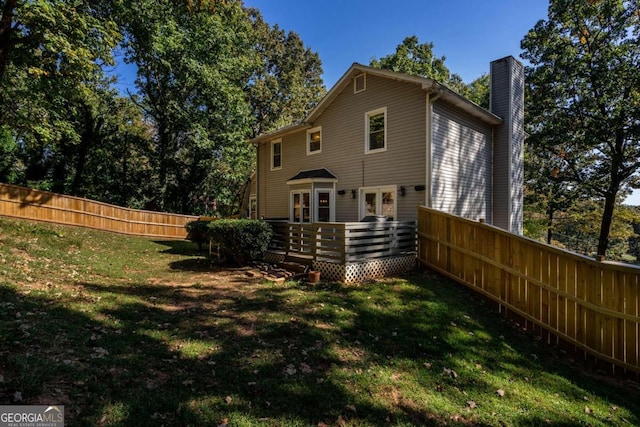 back of property with a deck and a yard