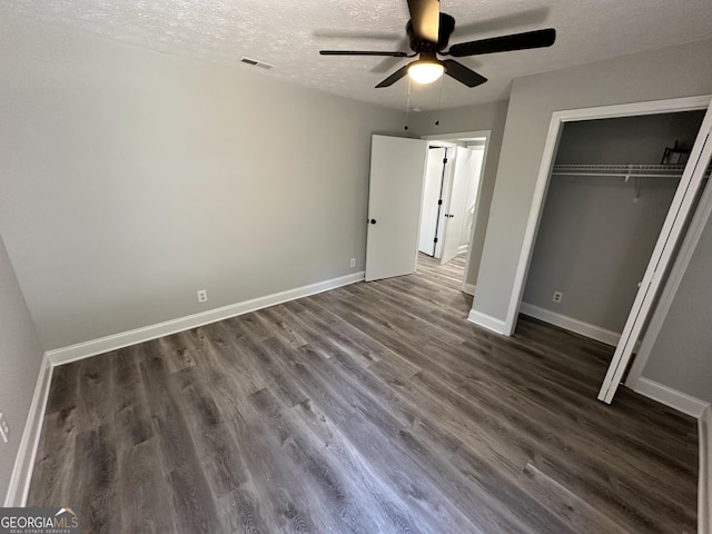 unfurnished bedroom with dark hardwood / wood-style floors, a textured ceiling, ceiling fan, and a closet