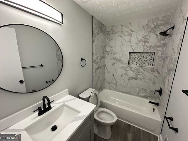 full bathroom featuring toilet, a textured ceiling, vanity, tiled shower / bath combo, and hardwood / wood-style floors