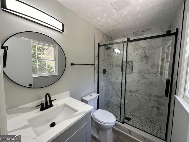 bathroom featuring vanity, toilet, a textured ceiling, and walk in shower