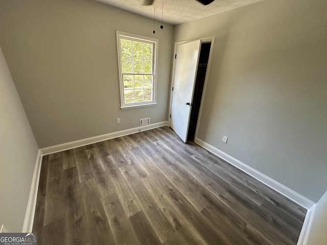 empty room with dark wood-type flooring, ceiling fan, and a textured ceiling