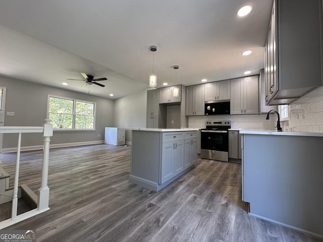 kitchen with pendant lighting, dark wood-type flooring, appliances with stainless steel finishes, gray cabinetry, and backsplash